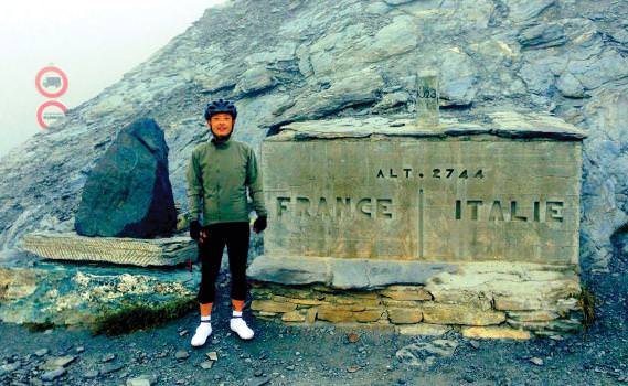 Chikashi Miyamoto pauses on Day 3 at the border between France and Italy, at an altitude of 2744 meters, during the Turin-Monte Carlo cycling challenge.